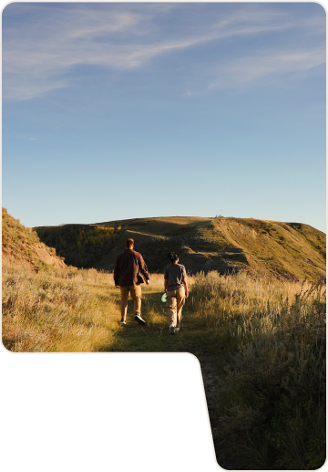 Hero Image - two people walking over grassy dunes